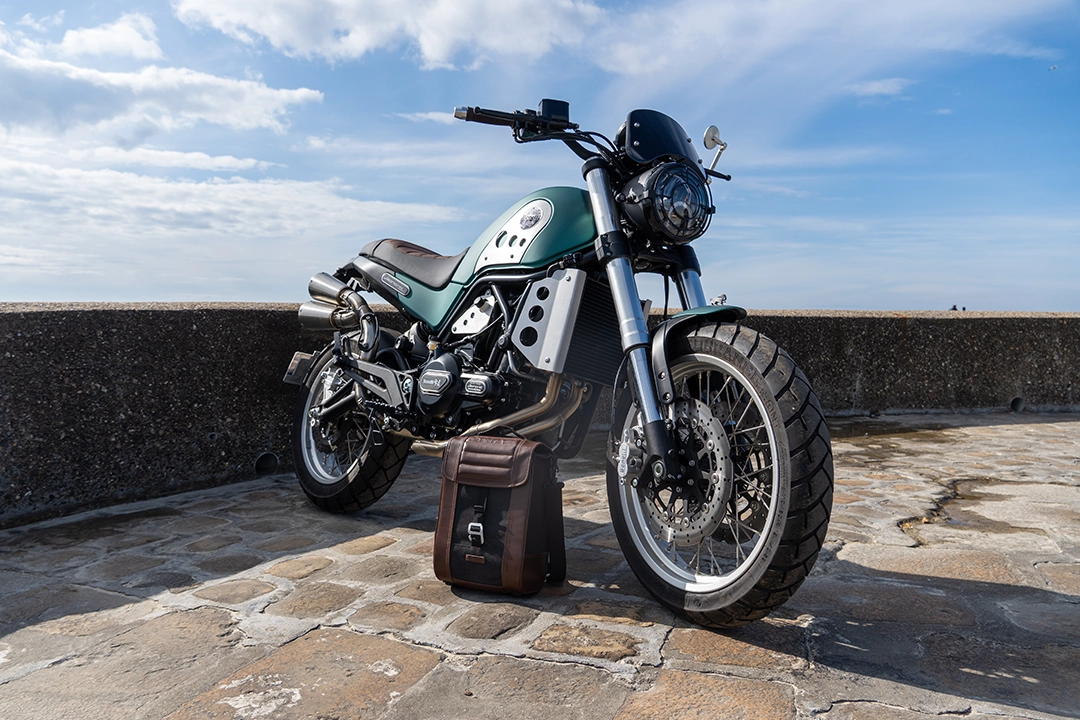 Moto avec sacoche au sol avec un ciel bleu derrière